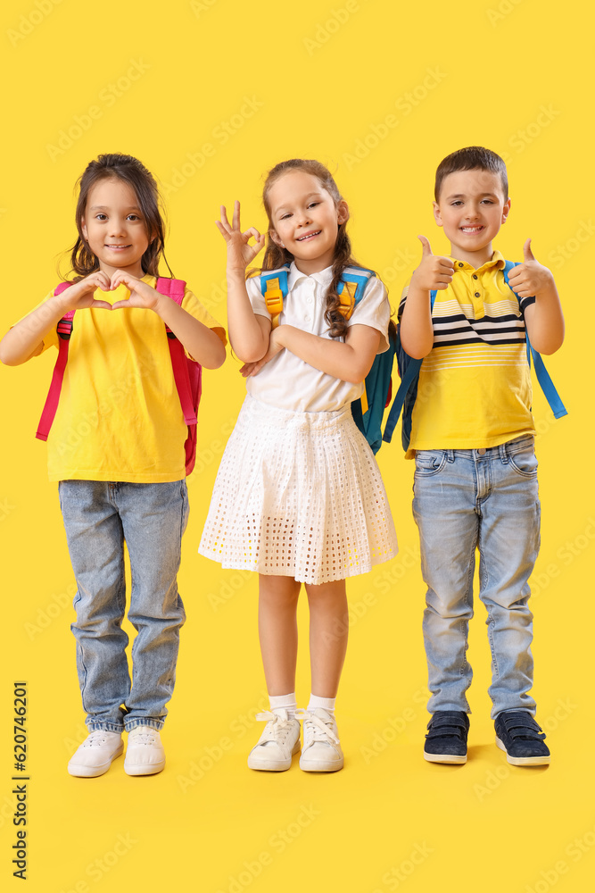 Little schoolchildren showing different gestures on yellow background