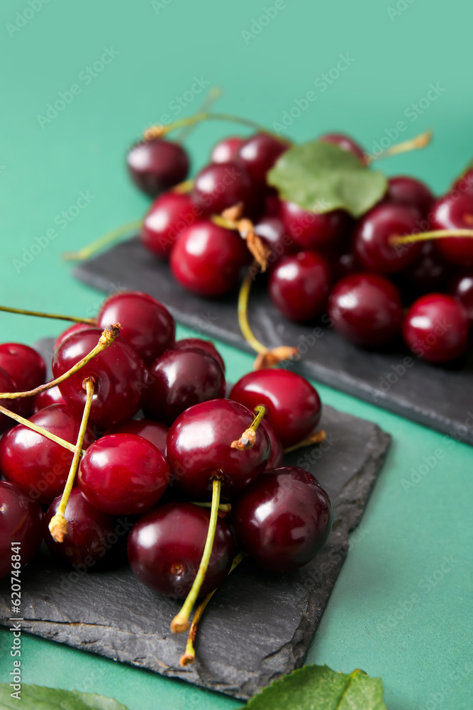 Boards with sweet cherries on green background