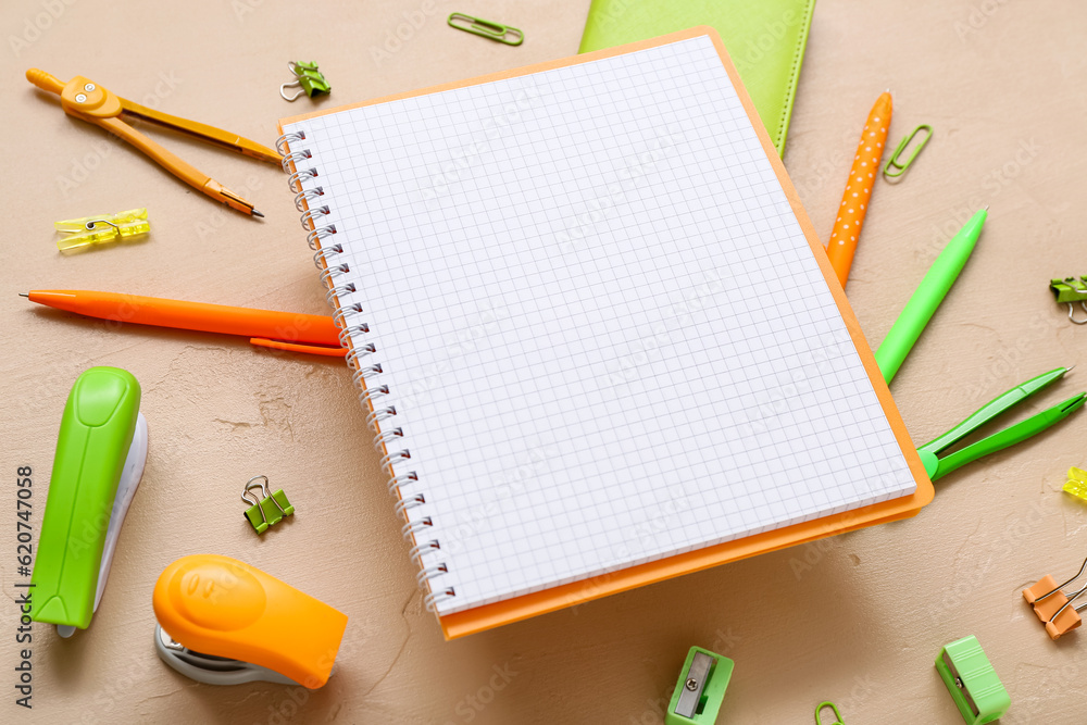 Blank notebook and different stationery on beige background