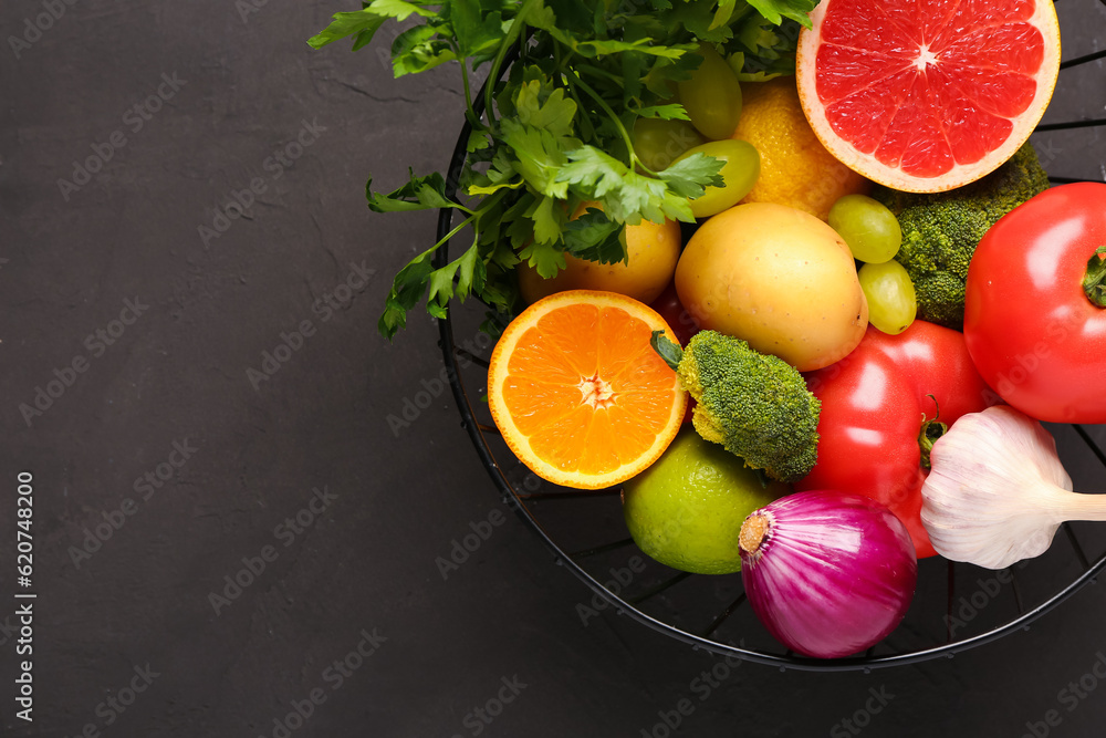 Basket with different fresh fruits and vegetables on black background, closeup