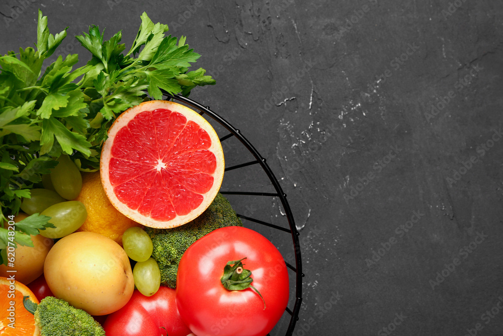 Basket with different fresh fruits and vegetables on black background, closeup