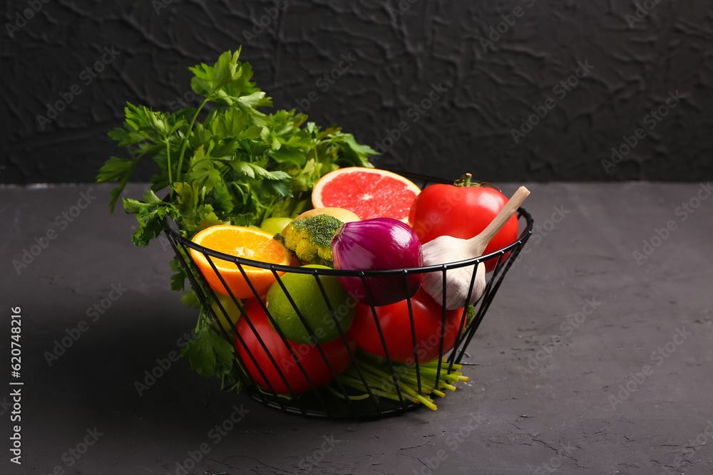 Basket with different fresh fruits and vegetables on black background