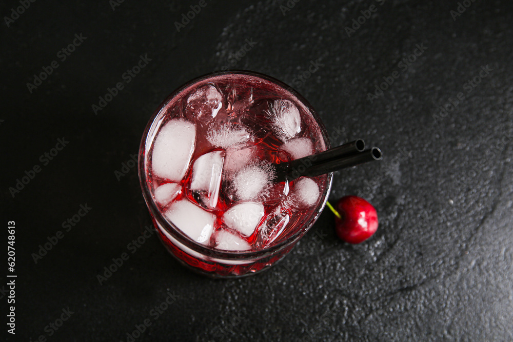 Glass of tasty cherry lemonade on black background