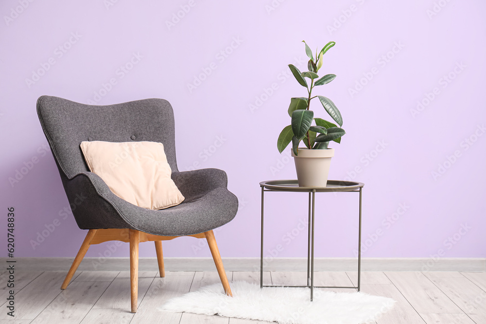 Armchair, table and houseplant near lilac wall