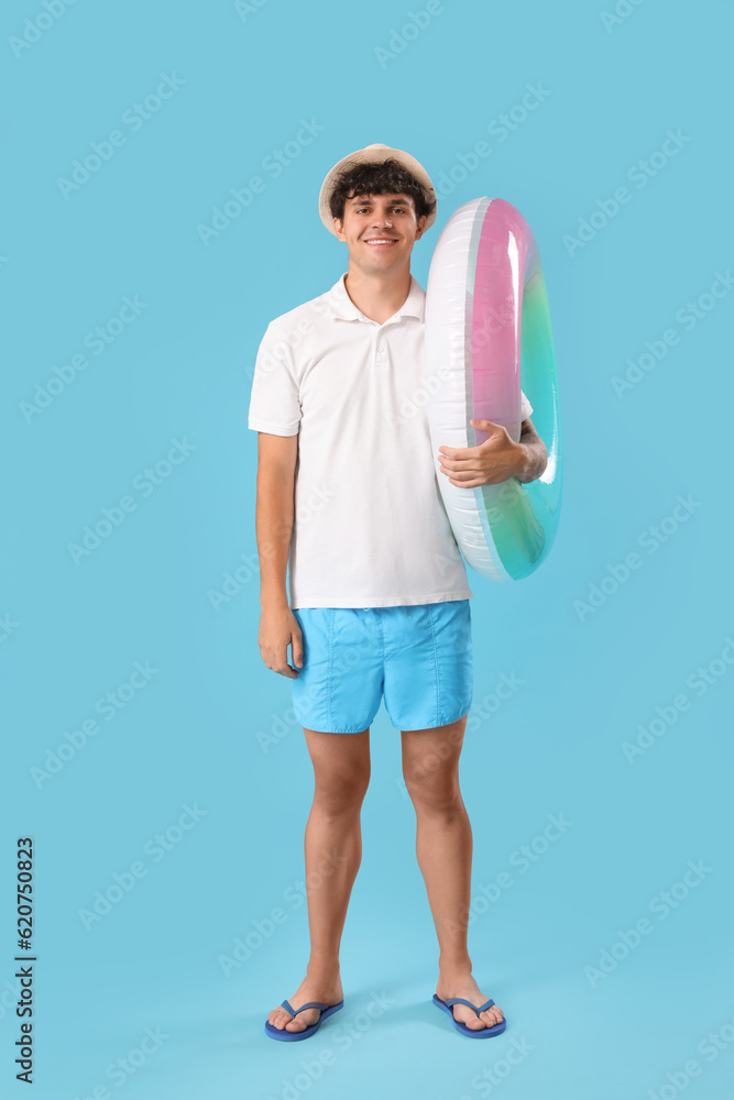 Young man with swim ring on blue background