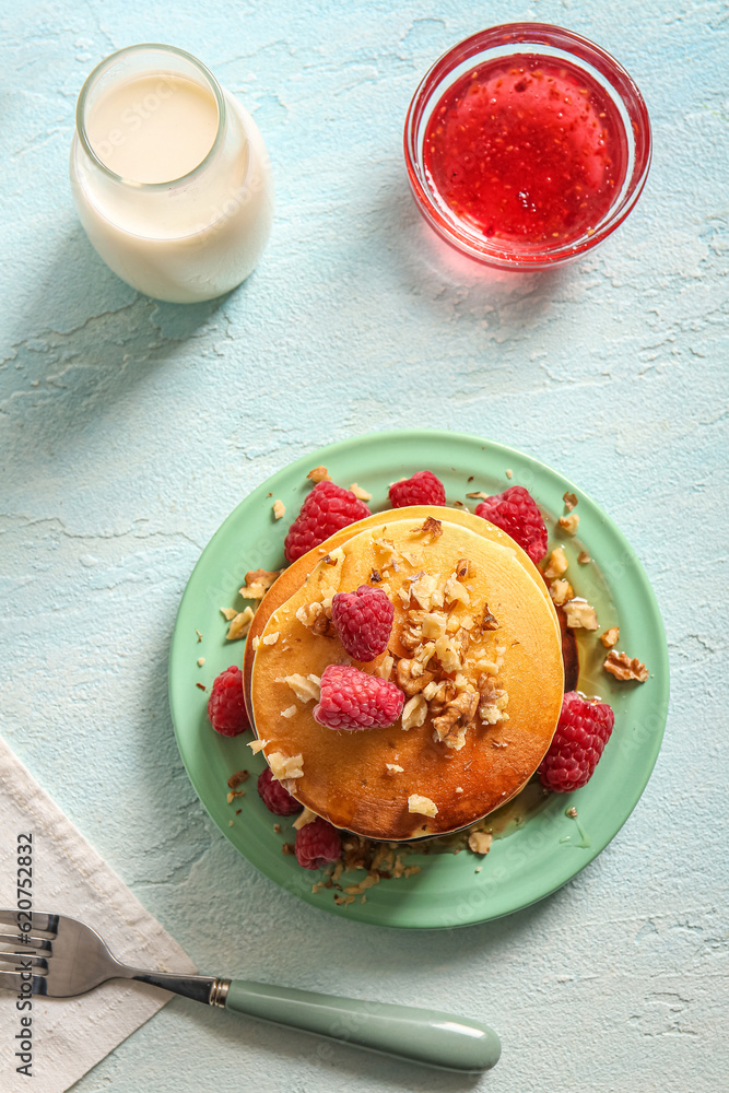 Plate of tasty pancakes with raspberries on light background