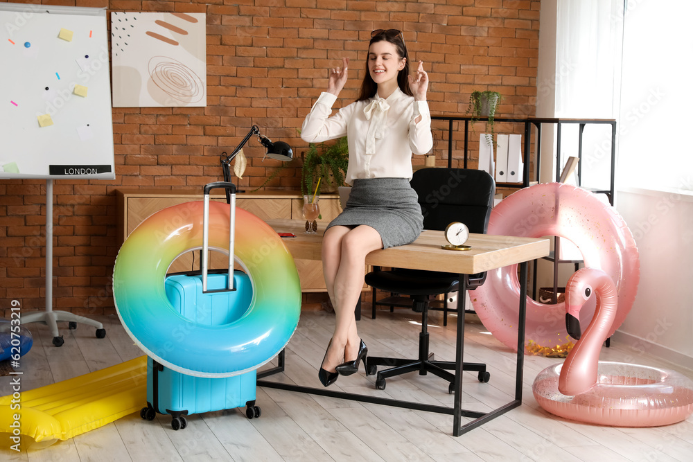 Young businesswoman ready for summer vacation crossing fingers in office