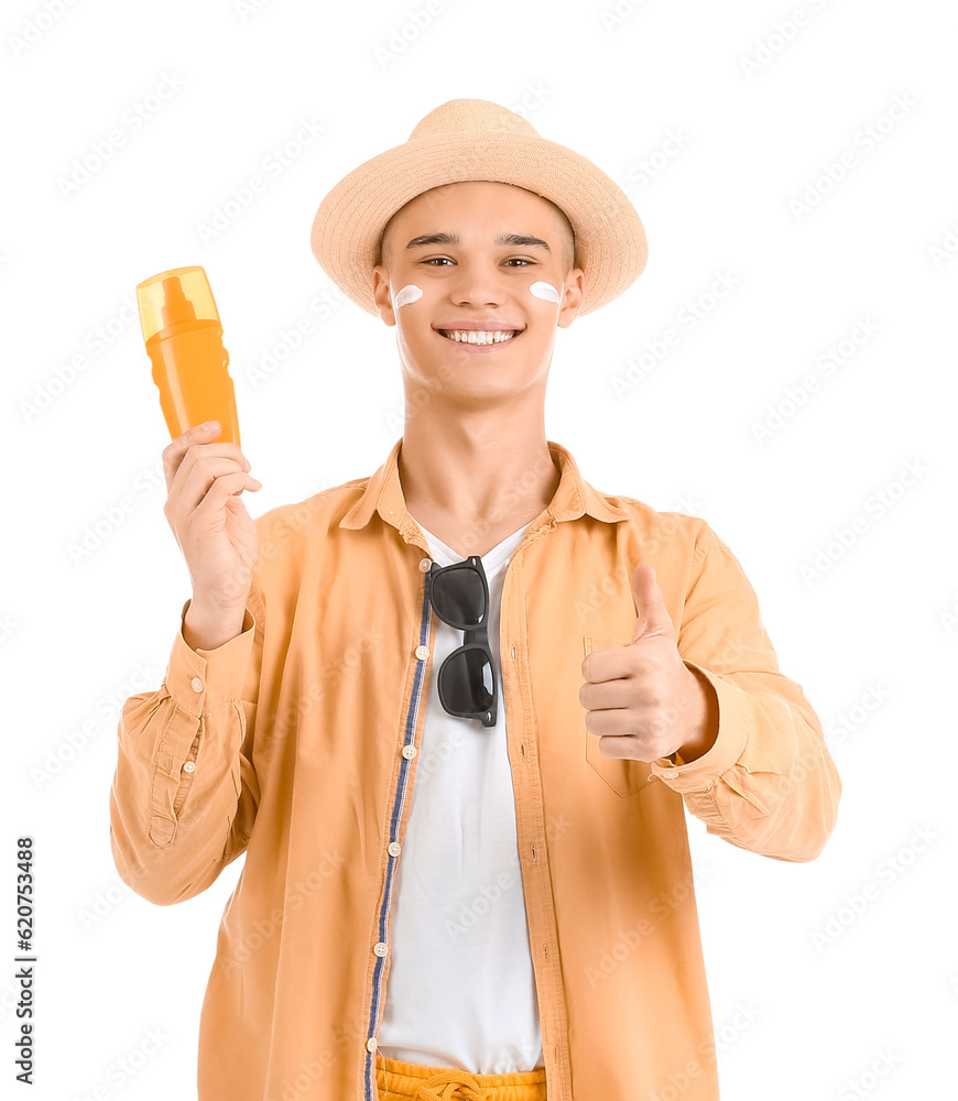 Happy young man with sunscreen cream on his face showing thumb-up gesture against white background