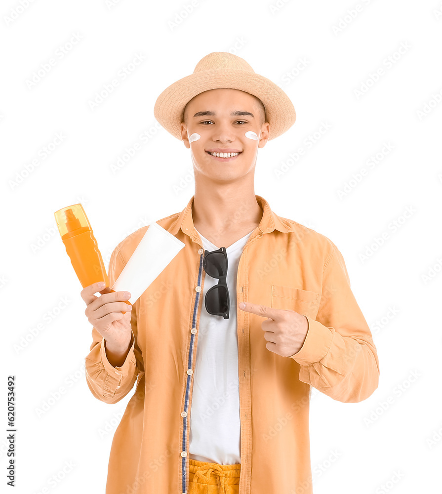 Happy young man pointing at bottles of sunscreen cream isolated on white background