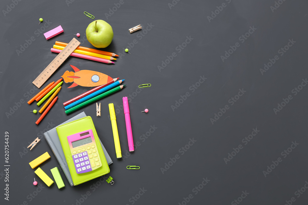 Paper rocket with school stationery and apple on black background