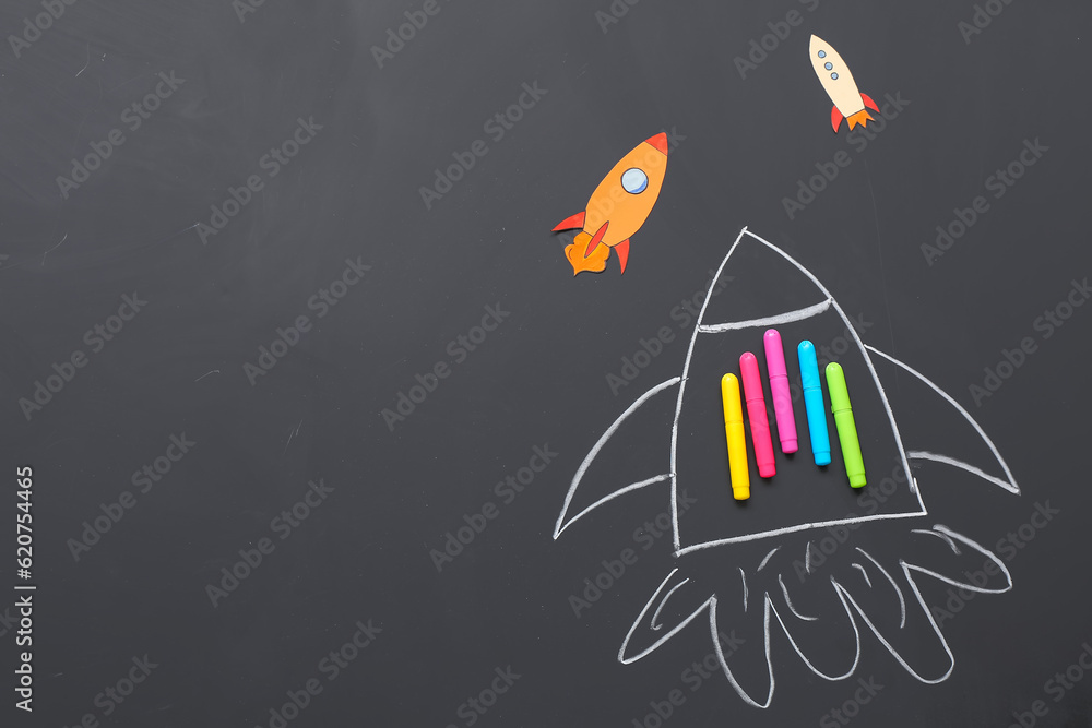 Drawn and paper rockets with markers on black background