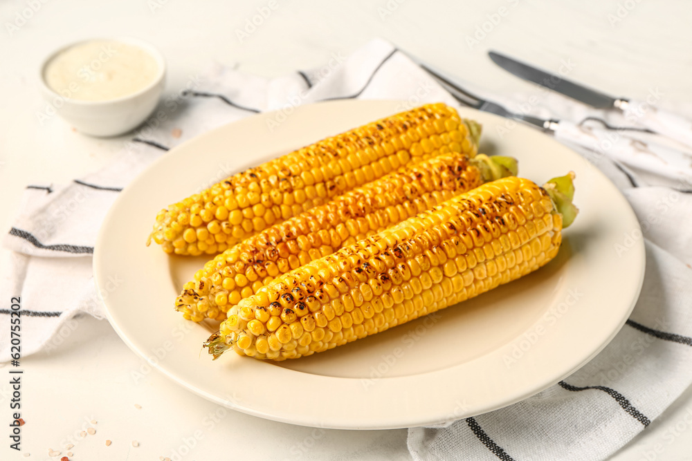 Plate with tasty grilled corn cobs and sauce on white background