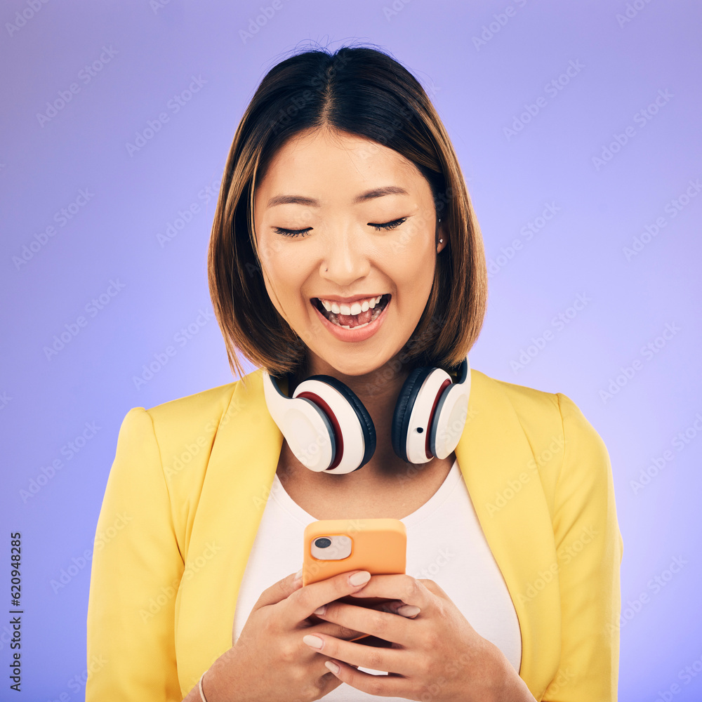 Headphones, phone and happy Asian woman in studio smile for social media, internet meme and chat. Te