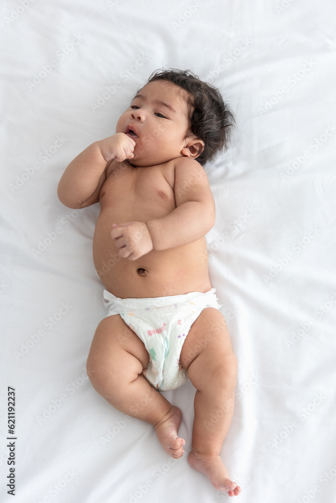 Portrait Asian Newborn baby girl wear diapers sleep on a soft white bed. cute infant isolated