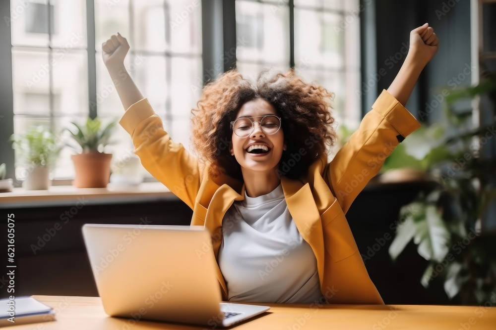 Joyful business woman freelancer entrepreneur smiling and rejoices in victory while sitting at desk 