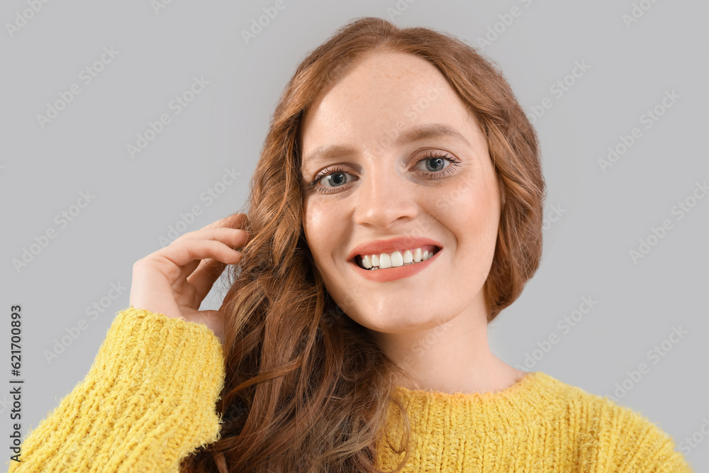 Beautiful woman with red hair on grey background, closeup