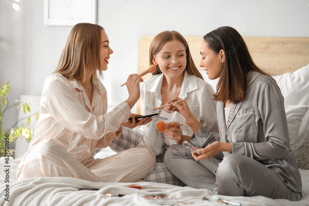 Young women doing makeup in bedroom