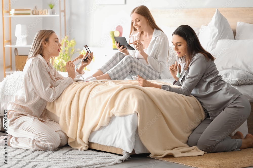 Young women doing makeup in bedroom