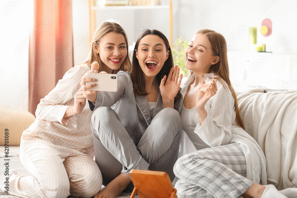 Young women with applied makeup taking selfie in bedroom