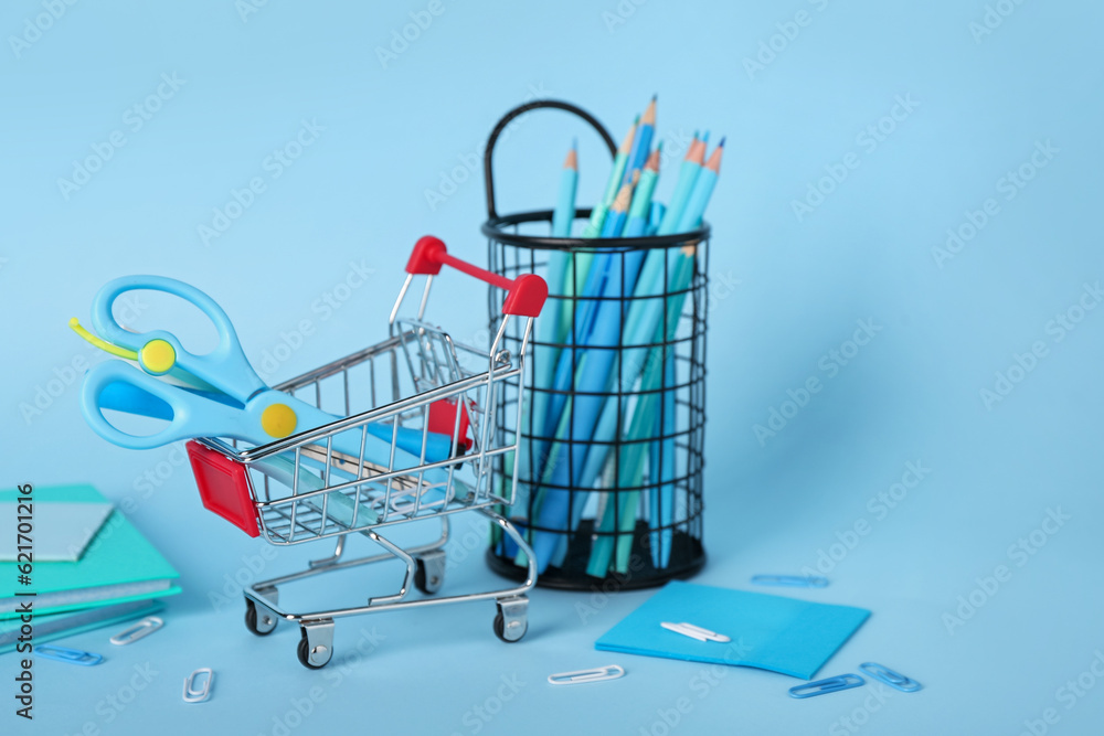 Shopping cart with stationery on blue background