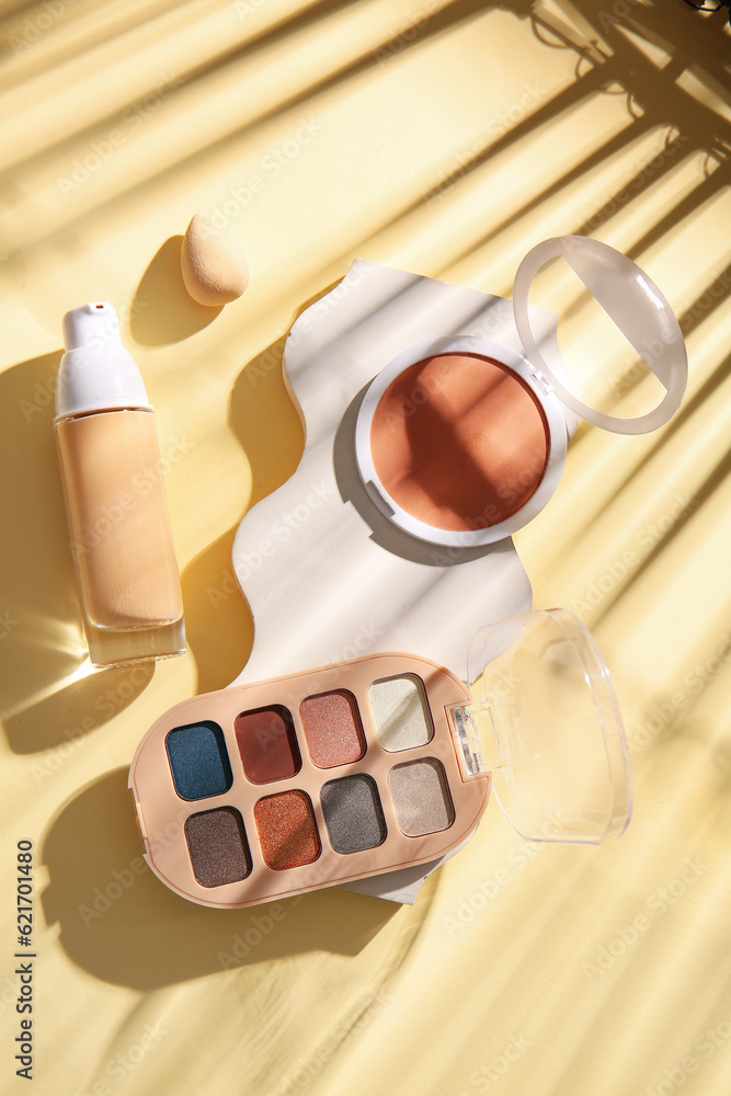 Composition with decorative cosmetics and makeup sponge on color background