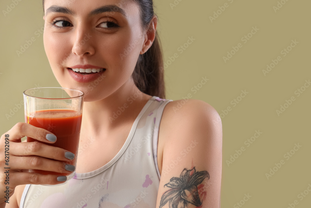 Sporty young woman with glass of vegetable juice on green background, closeup