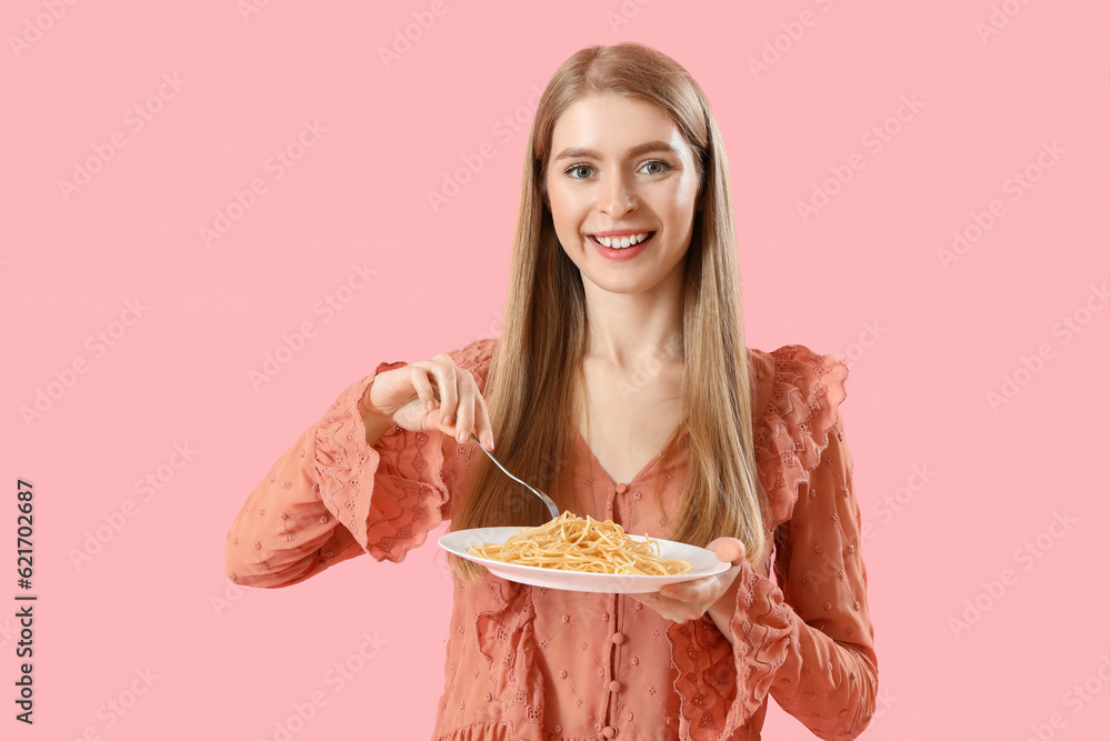 Young woman with tasty pasta on pink background