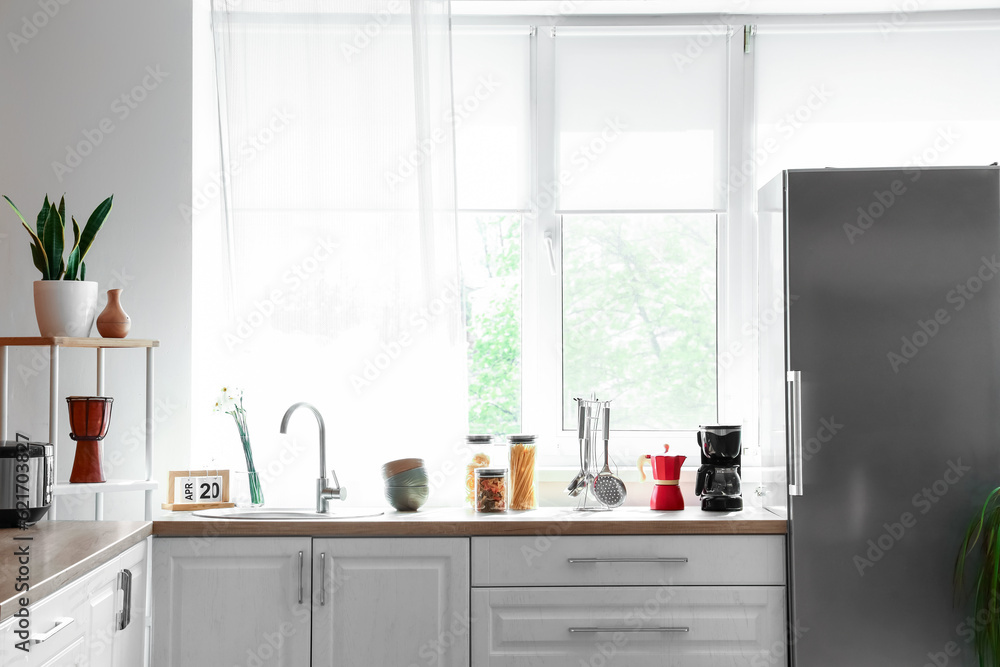 Interior of kitchen with stylish fridge, counters and window