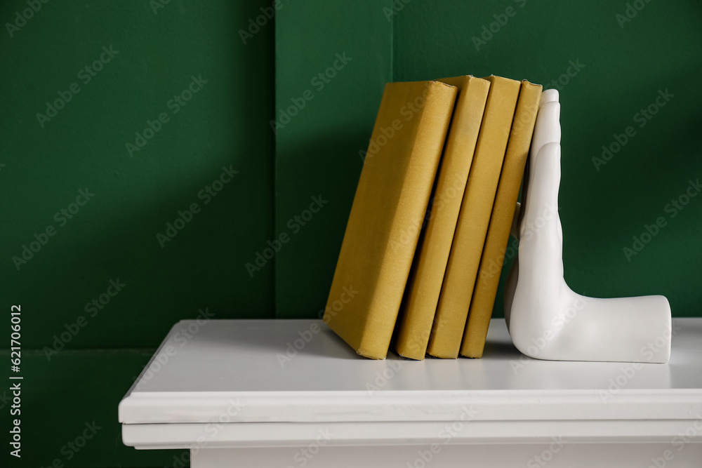 Stylish bookend on fireplace near green wall