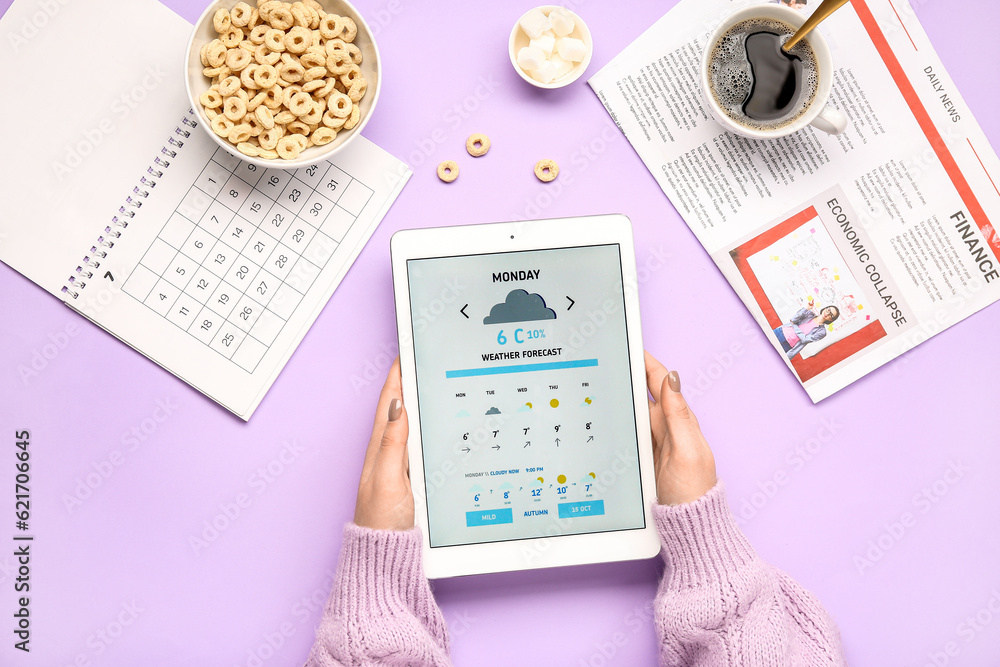 Woman holding tablet computer with weather forecast on lilac background