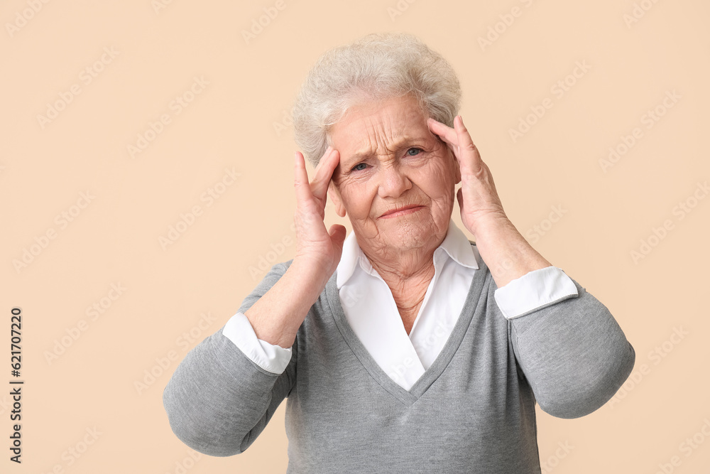 Stressed senior woman on beige background