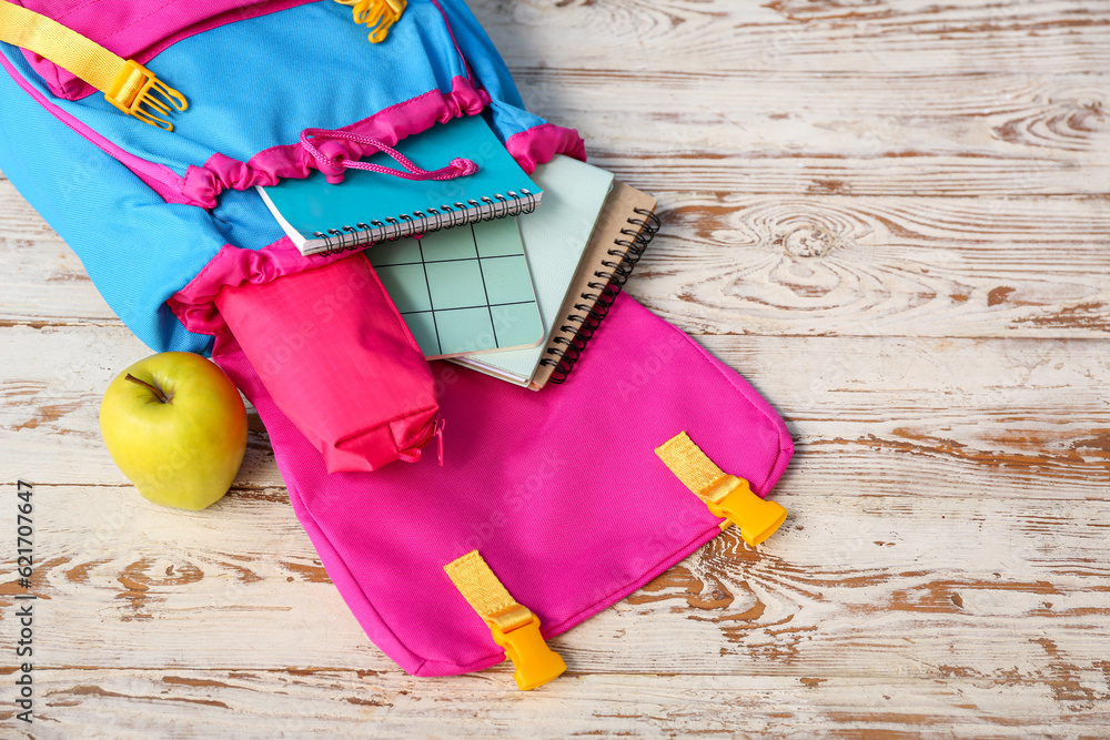 Color school backpack with notebooks, pencil case and apple on wooden table