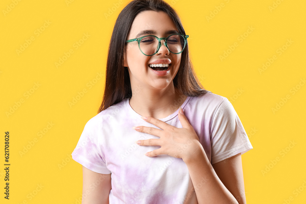 Happy young woman wearing glasses on yellow background