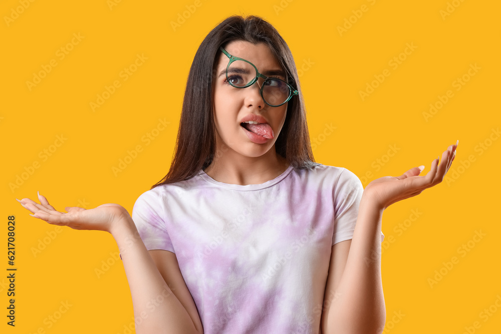 Crazy young woman wearing glasses on yellow background