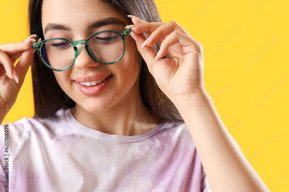 Pretty young woman wearing glasses on yellow background