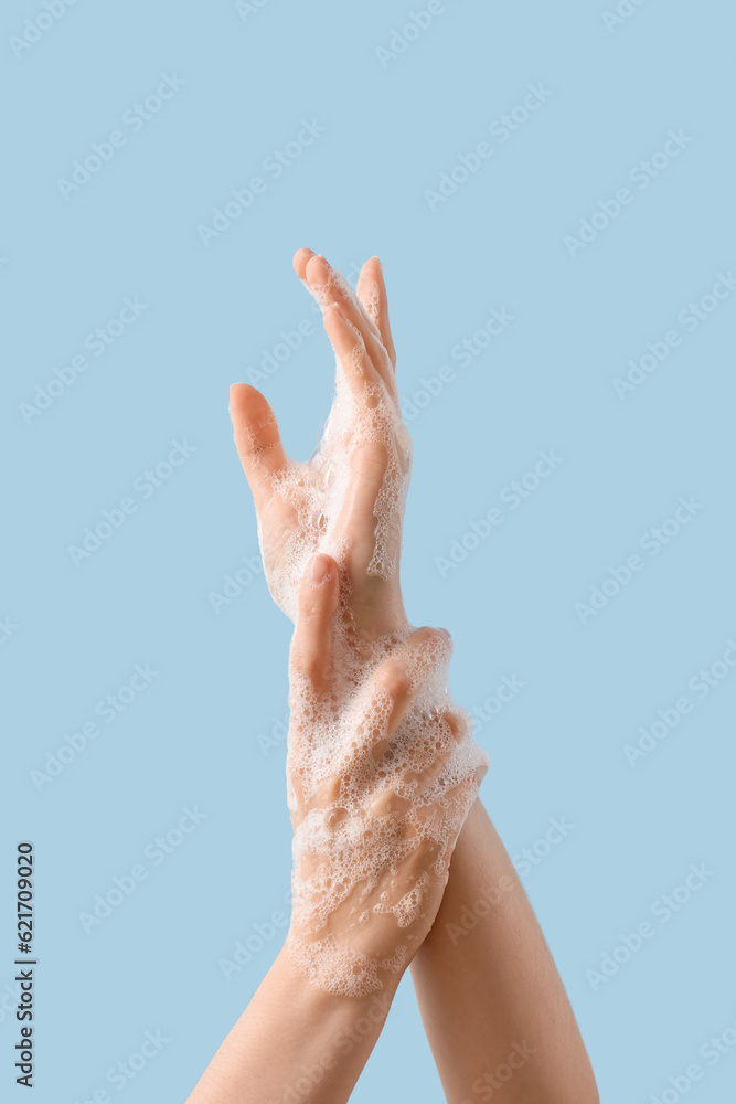 Hands in soap foam on light blue background