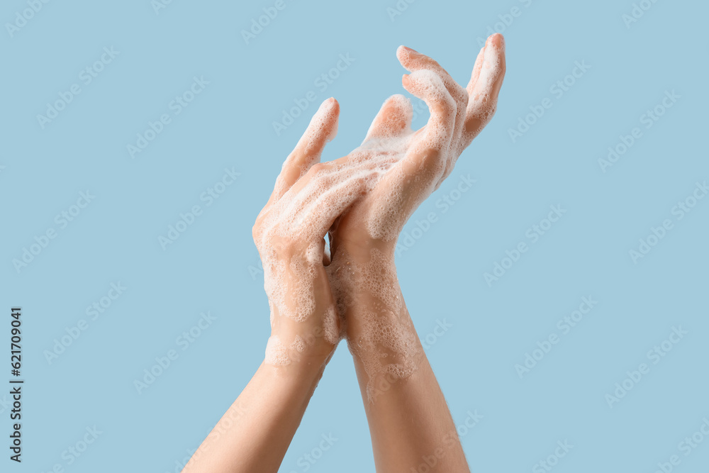 Hands in soap foam on light blue background