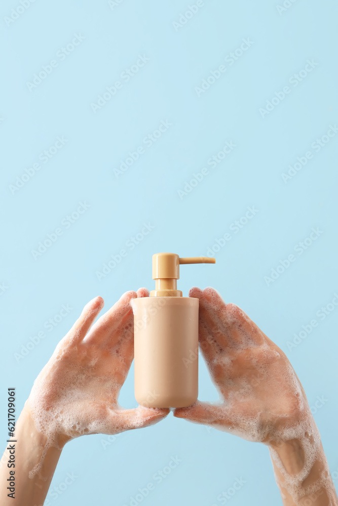 Hands with liquid soap on light blue background