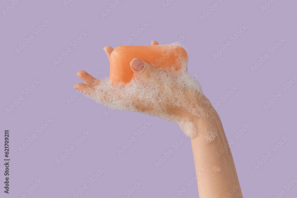 Hand with soap on lilac background