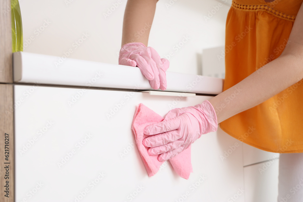 Woman cleaning white counter with rag in kitchen, closeup