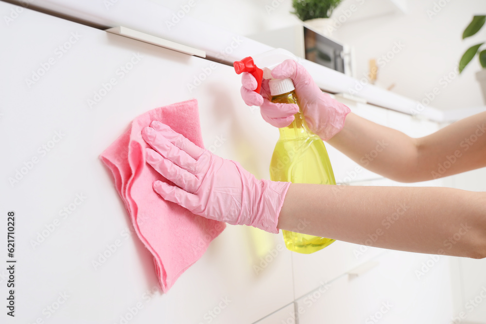 Woman cleaning white counter with rag in kitchen, closeup