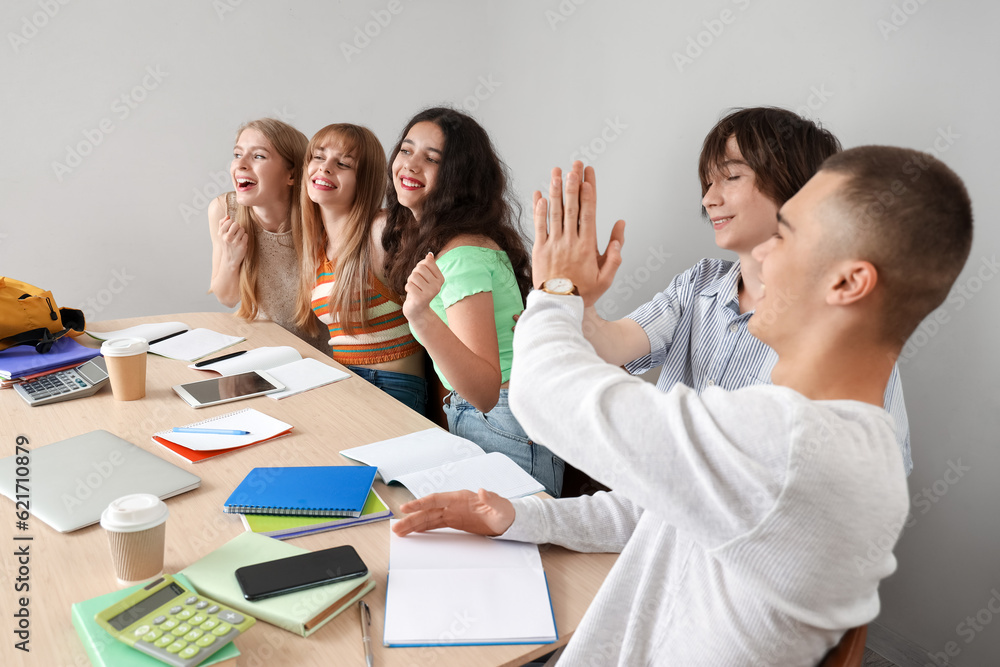 Happy students doing homework at table in room