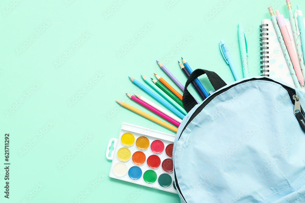 School backpack with different colorful pencils and paints on turquoise background