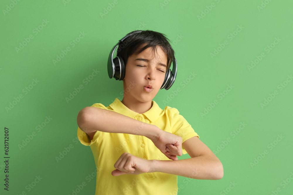 Little boy in headphones dancing on green background