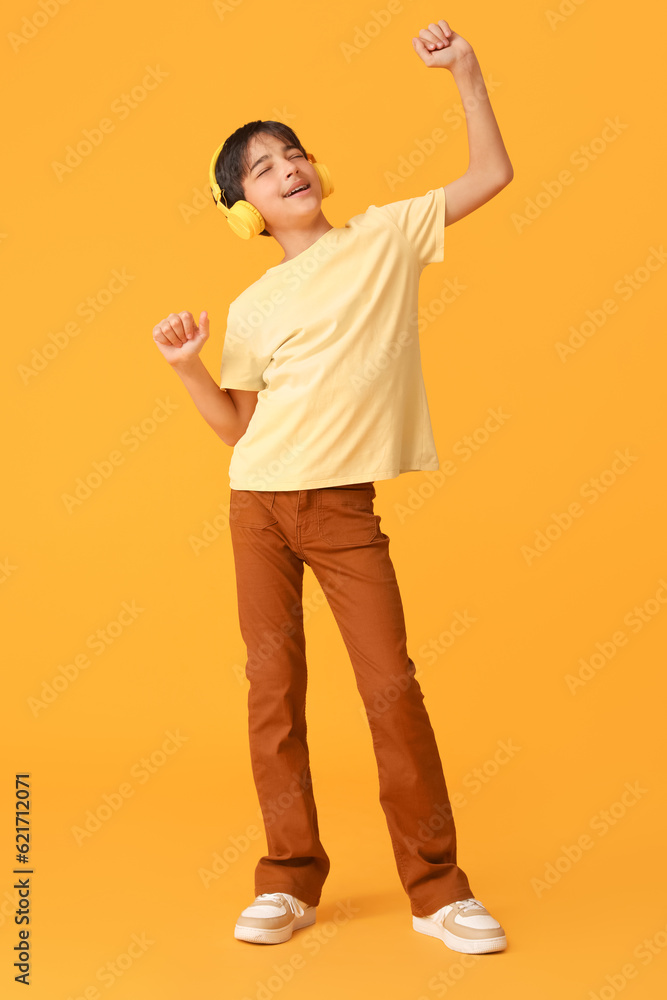 Little boy in headphones dancing on orange background