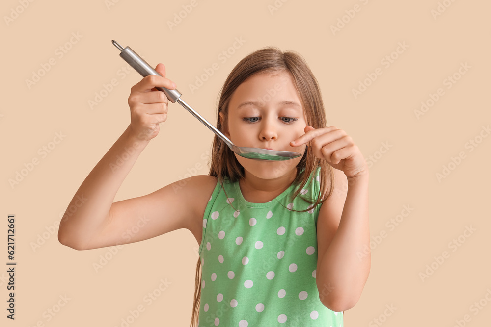 Little girl with ladle on beige background