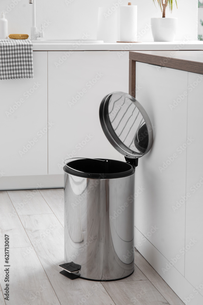 Opened trash bin in interior of light kitchen