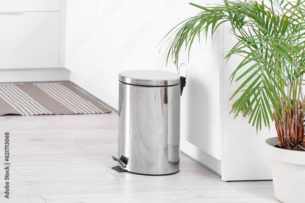 Metallic trash bin in interior of light kitchen