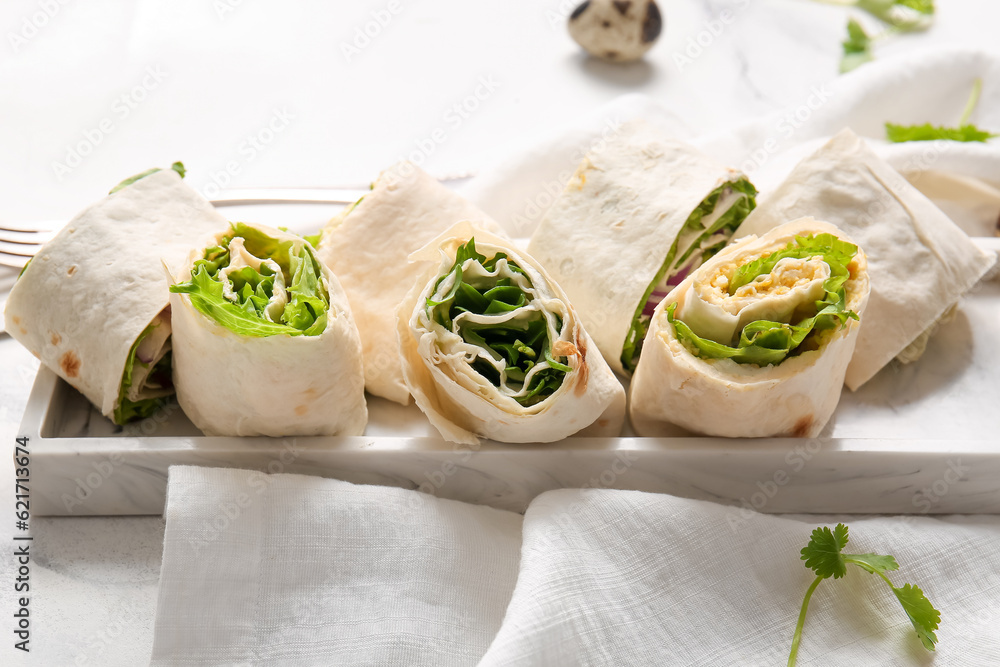 Plate of tasty lavash rolls with egg, onion and greens on white marble background