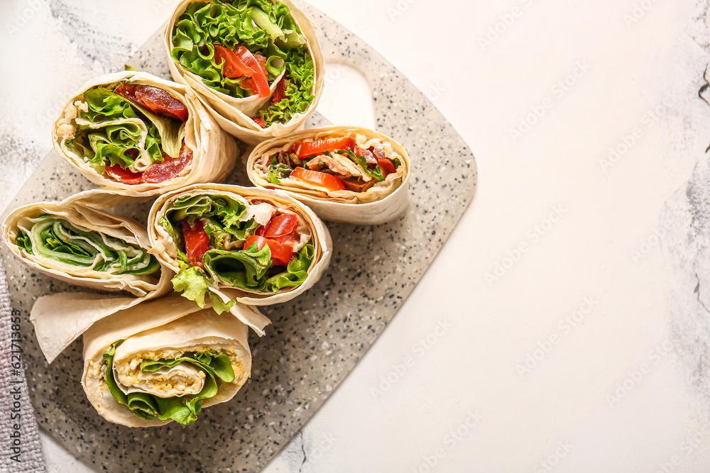 Board of tasty lavash rolls with tomatoes, egg and greens on white marble background